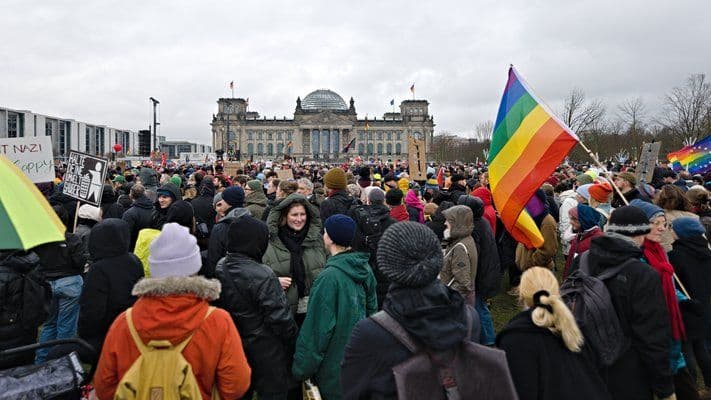 Menschen vor dem Reichstag mit Regenbogenfahnen