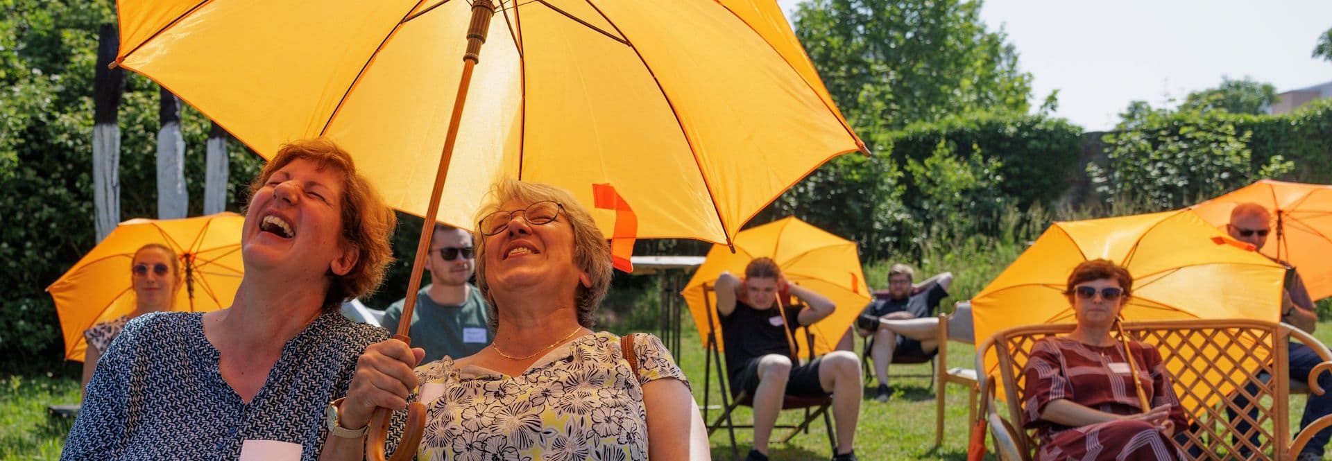Zwei ältere Frauen schreien/singen unter einem Regen/Sonnenschirm