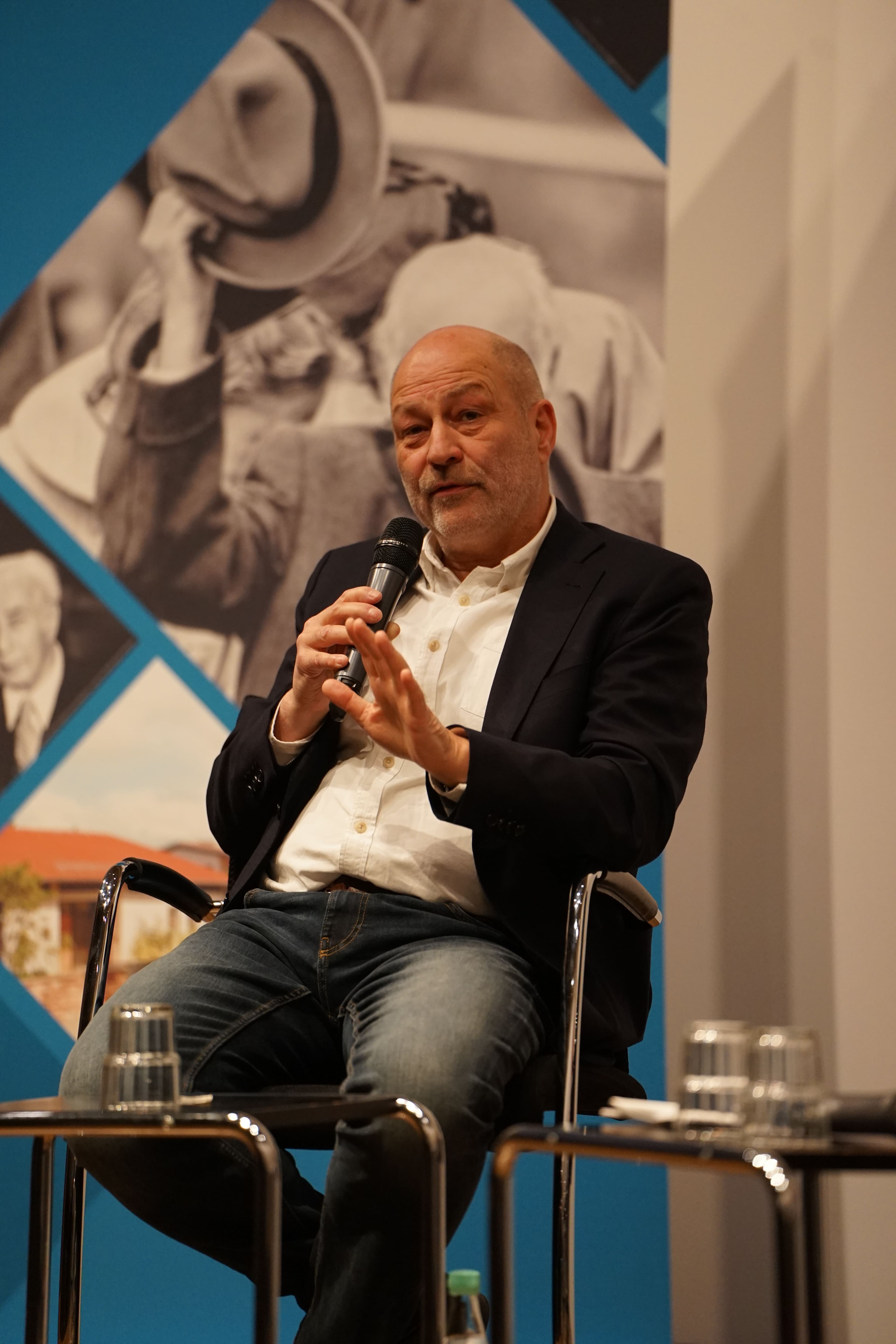 Foto von Ralf Uwe Beck auf einer Bühne mit Mikrofon