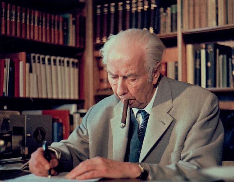 Portrait von Theodor Heuss in einem Büro mit vielen Büchern und einer Zigarre im Mund.