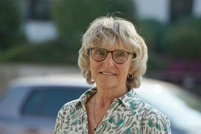 Porträt von Karin Golda mit Brille und kurzen blonden Haaren vor einem unscharfen Außenhintergrund