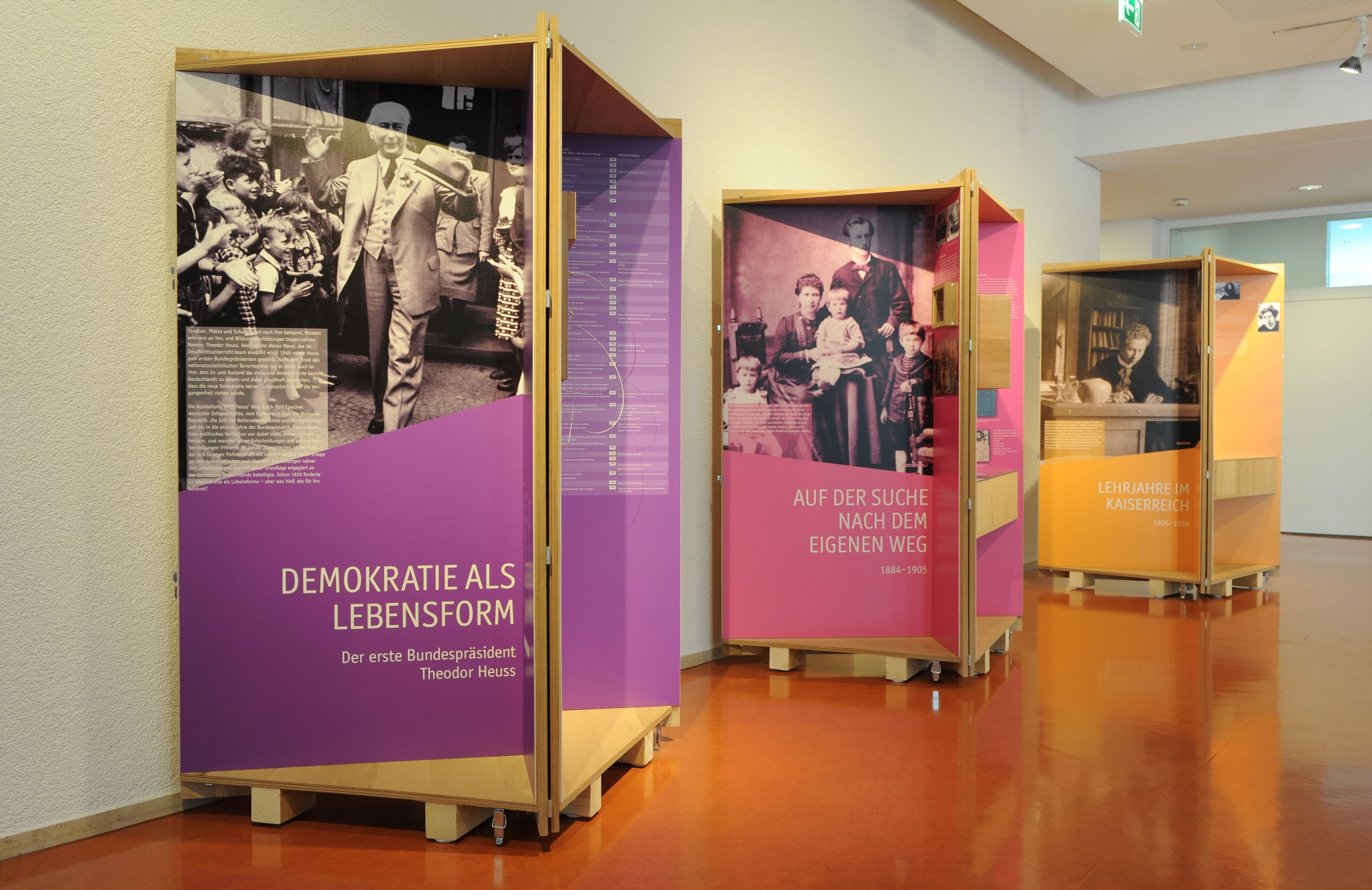 Detailansicht einer interaktiven Station der Ausstellung ‚Demokratie als Lebensform‘. In einem pinkfarbenen Regalmodul können Besucher Würfel mit historischen Porträts und Texten, wie zur ‚Deutschen Werkbund-Ausstellung 1914‘, haptisch erkunden und umdrehen.